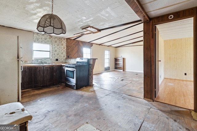 kitchen featuring wooden walls, gas stove, white refrigerator, and a healthy amount of sunlight