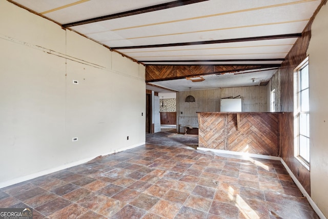 spare room featuring lofted ceiling with beams and wood walls