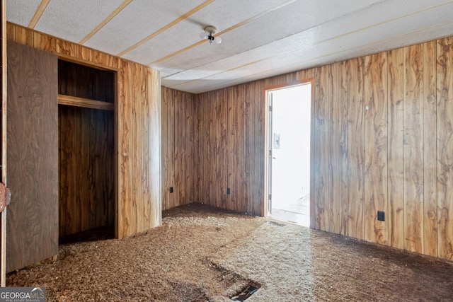 carpeted empty room featuring wooden walls