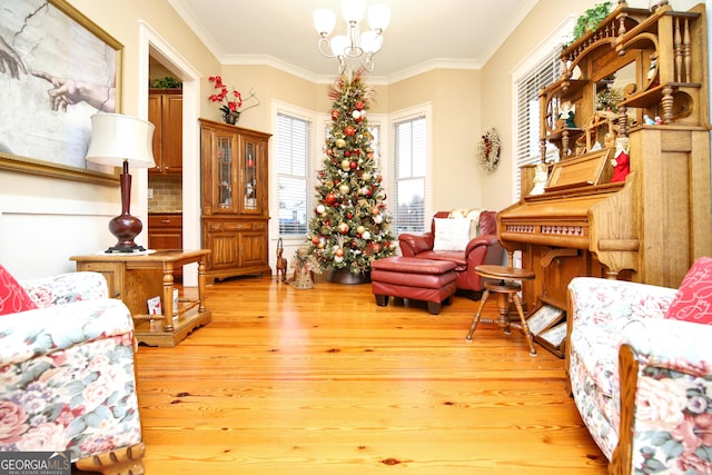 living area with a chandelier, crown molding, and wood-type flooring