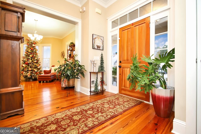 foyer featuring ornamental molding, a notable chandelier, and hardwood / wood-style flooring