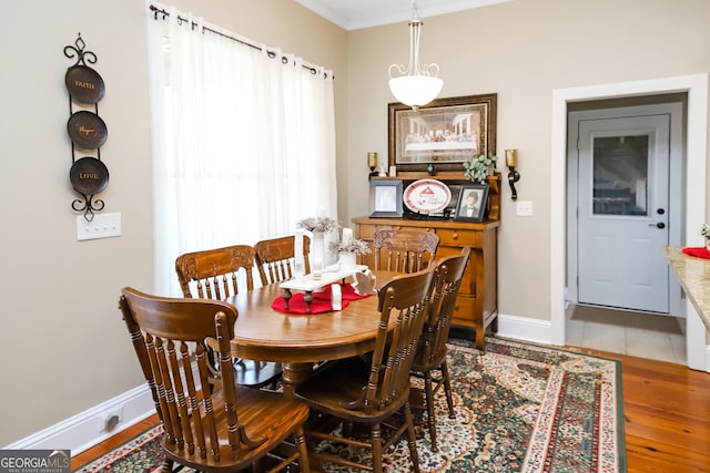 dining space with baseboards, wood finished floors, and ornamental molding