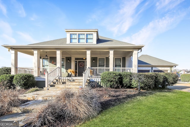 view of front of home with a porch, a front lawn, an attached garage, and a shingled roof