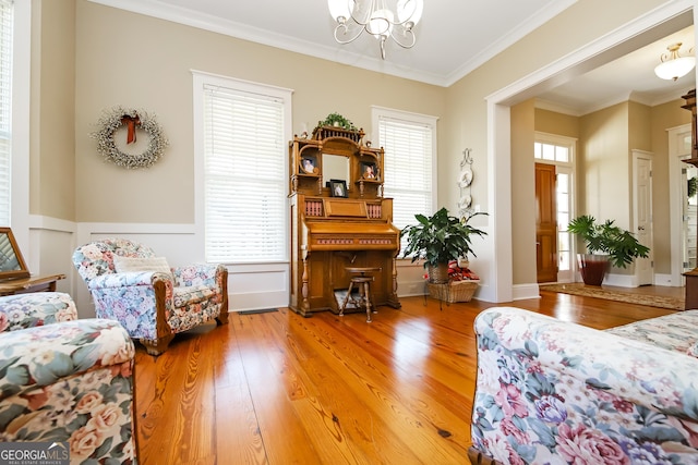 living area featuring a notable chandelier, ornamental molding, and wood finished floors