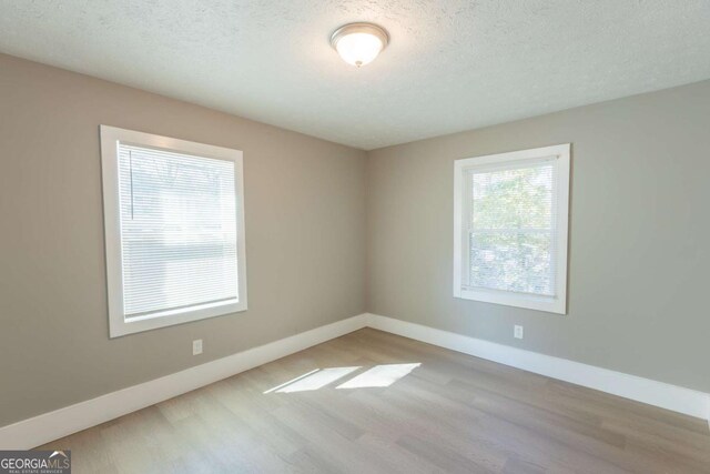 empty room featuring a textured ceiling and light hardwood / wood-style flooring