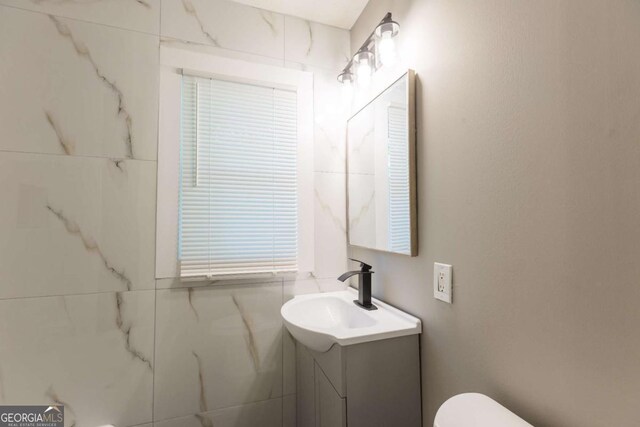 bathroom with vanity, tile walls, and toilet