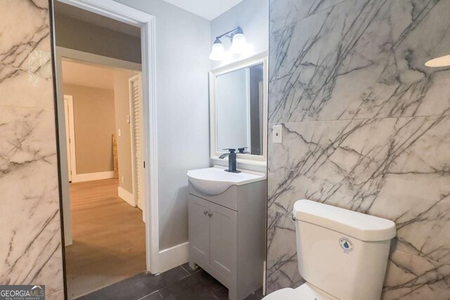 bathroom with vanity, tile walls, and toilet