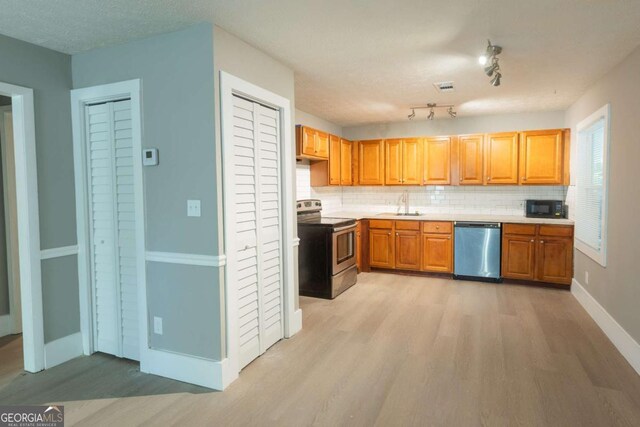 kitchen with sink, stainless steel appliances, backsplash, light hardwood / wood-style floors, and a textured ceiling