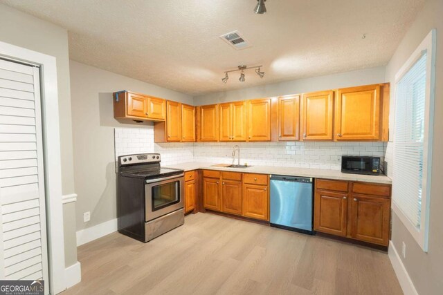 kitchen with tasteful backsplash, light hardwood / wood-style floors, a textured ceiling, and appliances with stainless steel finishes