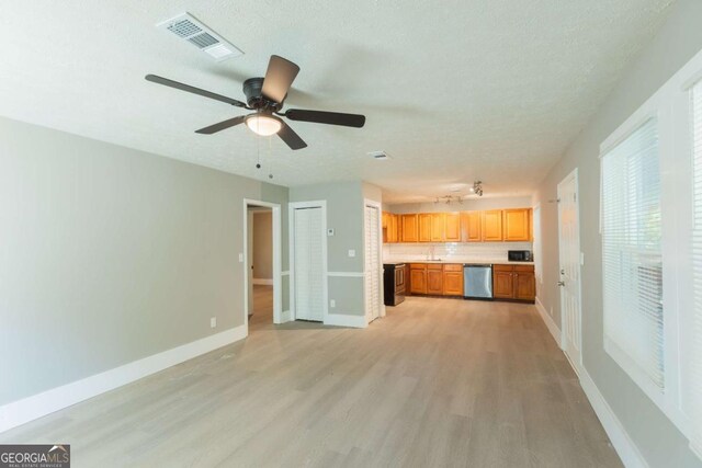 unfurnished living room with ceiling fan, a textured ceiling, and light wood-type flooring