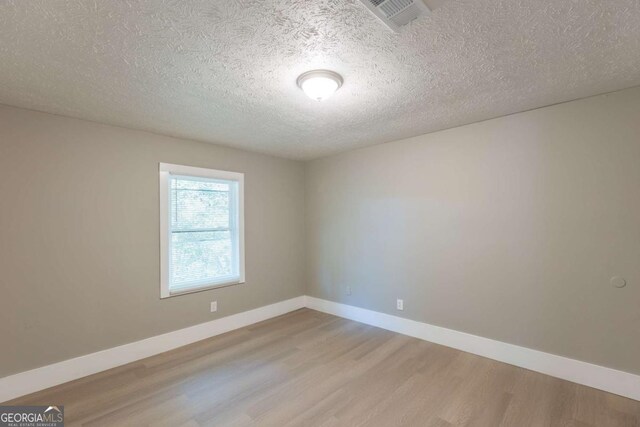 empty room featuring light wood-type flooring and a textured ceiling