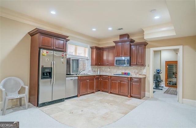 kitchen featuring tasteful backsplash, ornamental molding, stainless steel appliances, light colored carpet, and sink