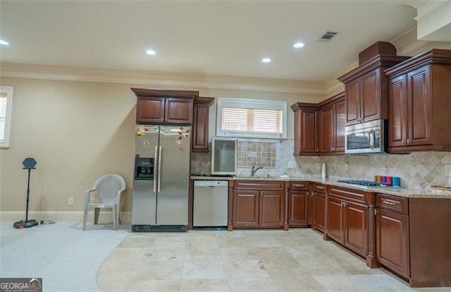 kitchen featuring light stone countertops, sink, stainless steel appliances, tasteful backsplash, and ornamental molding