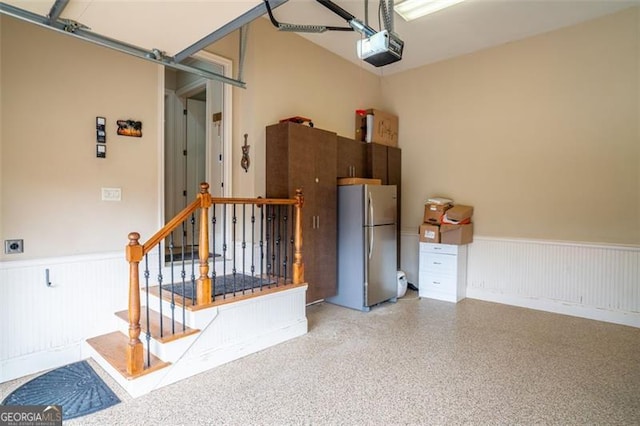 garage with a garage door opener and stainless steel refrigerator