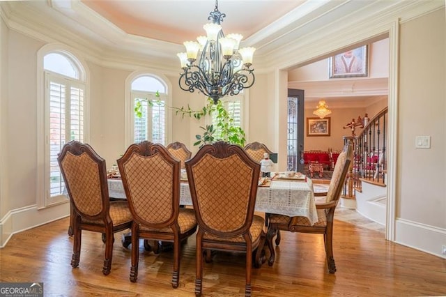 dining room featuring hardwood / wood-style flooring, an inviting chandelier, a tray ceiling, and crown molding