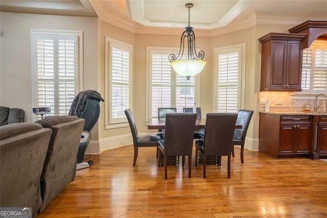 dining area with light hardwood / wood-style floors, crown molding, and sink