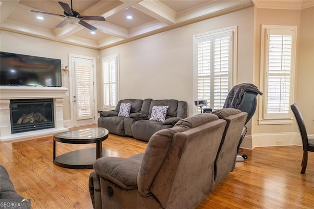 living room featuring ceiling fan, light hardwood / wood-style floors, coffered ceiling, and ornamental molding