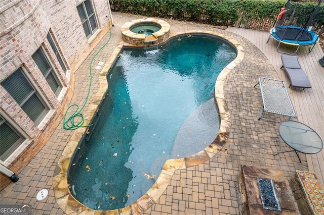 view of pool featuring an in ground hot tub and a trampoline