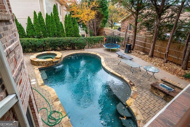 view of swimming pool featuring a trampoline, an in ground hot tub, and a patio