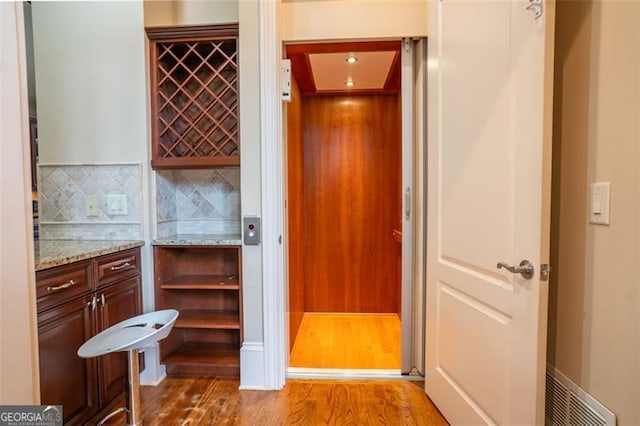 bathroom with wood-type flooring, backsplash, and elevator