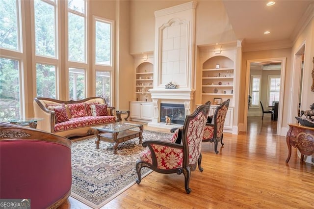 living room with a fireplace, light hardwood / wood-style flooring, a healthy amount of sunlight, and built in features