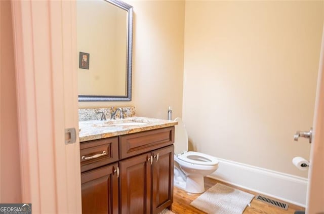 bathroom with vanity, toilet, and wood-type flooring