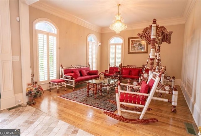 sitting room with an inviting chandelier, ornamental molding, and hardwood / wood-style flooring