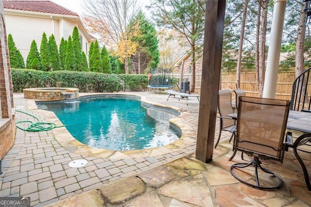 view of swimming pool featuring an in ground hot tub, a patio, and a trampoline