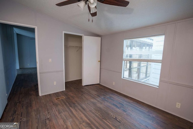 unfurnished bedroom featuring vaulted ceiling, dark hardwood / wood-style floors, ceiling fan, a textured ceiling, and a closet