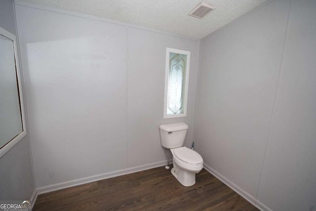 bathroom with hardwood / wood-style floors, a textured ceiling, and toilet