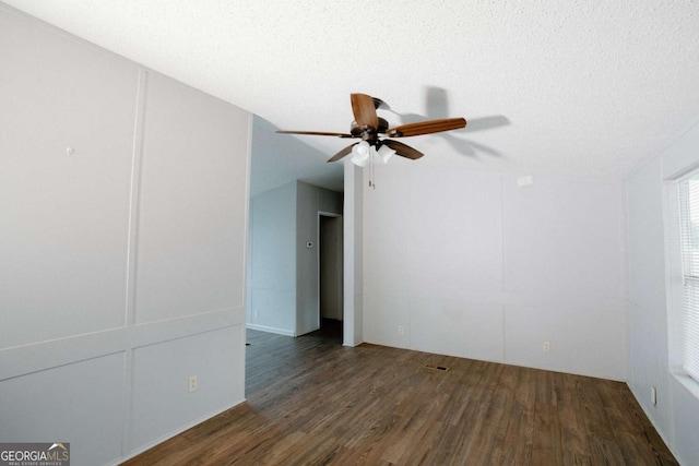 empty room with ceiling fan, dark hardwood / wood-style flooring, and a textured ceiling