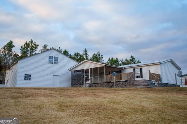 rear view of house featuring a sunroom and a lawn