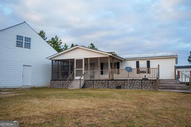 back of property with a sunroom and a lawn