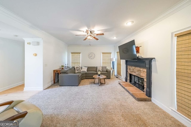 living room with a fireplace, light colored carpet, ceiling fan, and ornamental molding