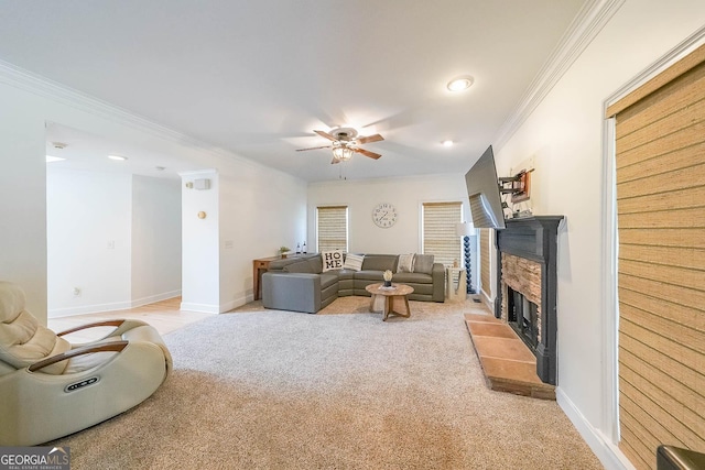 carpeted living room featuring a stone fireplace, ceiling fan, and crown molding