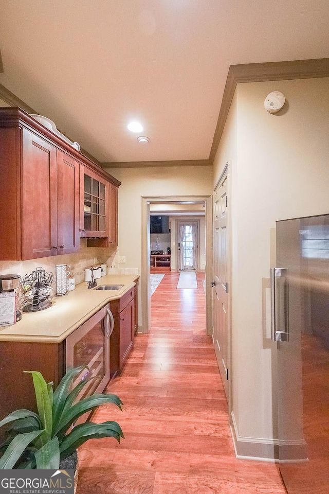 kitchen with crown molding, light wood-type flooring, sink, and wine cooler