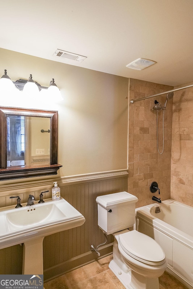 full bathroom with tiled shower / bath combo, toilet, and sink