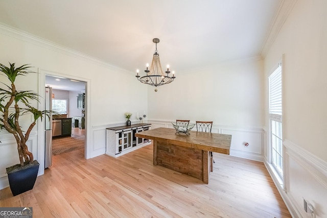 dining room with a notable chandelier, light wood-type flooring, and ornamental molding