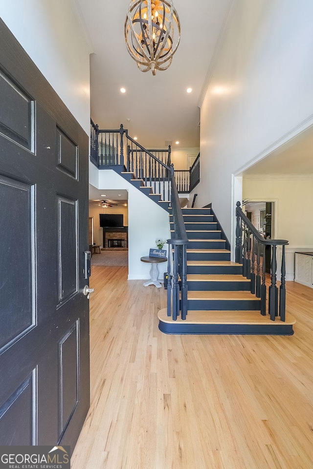 foyer entrance with light hardwood / wood-style floors, an inviting chandelier, and ornamental molding