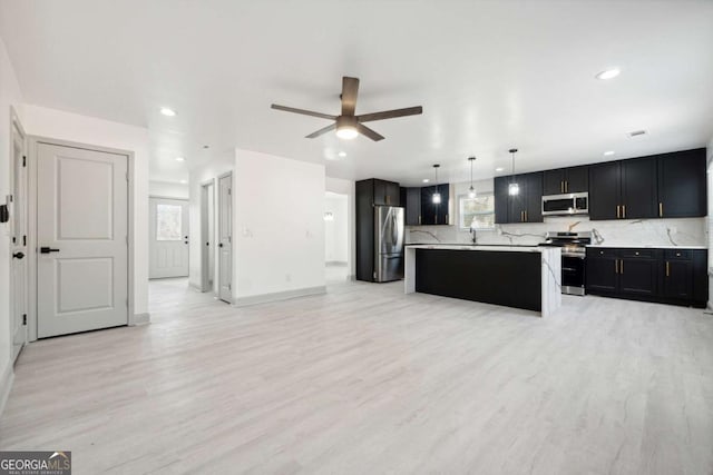 kitchen featuring a wealth of natural light, stainless steel appliances, pendant lighting, light hardwood / wood-style flooring, and a kitchen island