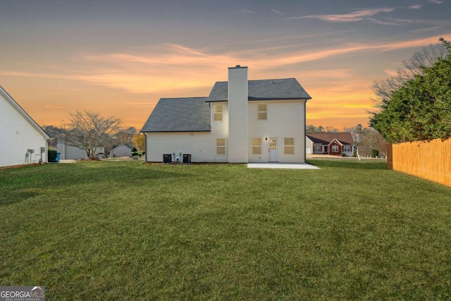 back house at dusk with a yard, cooling unit, and a patio