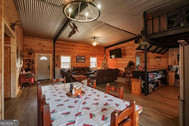 dining area with dark hardwood / wood-style flooring, wood ceiling, vaulted ceiling, wooden walls, and an inviting chandelier