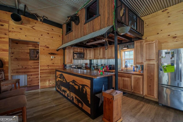 kitchen featuring wood walls, a center island, dark hardwood / wood-style flooring, and appliances with stainless steel finishes