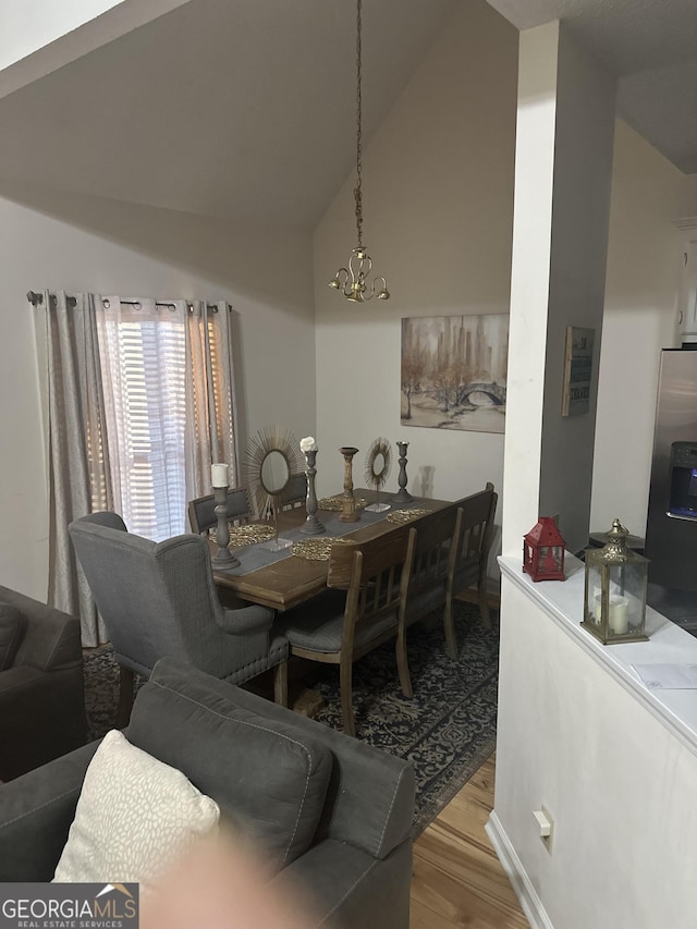 dining area featuring a chandelier, hardwood / wood-style flooring, and lofted ceiling