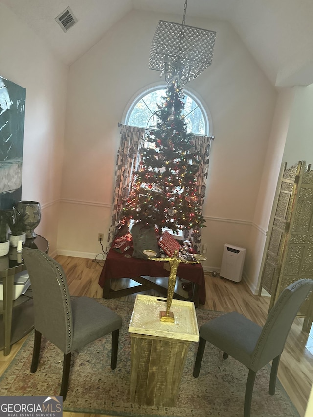 dining area featuring a chandelier, lofted ceiling, and light hardwood / wood-style flooring