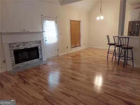 unfurnished living room featuring a notable chandelier, wood-type flooring, and a fireplace