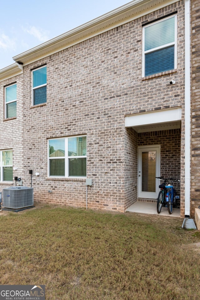 back of property featuring a patio, a yard, and central AC