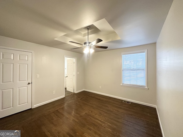 unfurnished room featuring a tray ceiling, ceiling fan, and dark hardwood / wood-style flooring