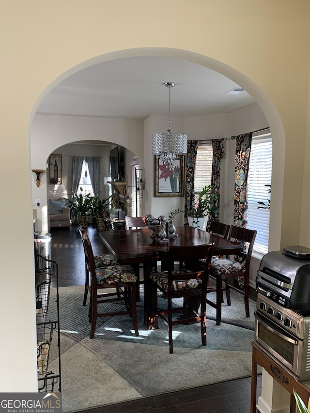 dining space featuring a notable chandelier, dark hardwood / wood-style floors, and a healthy amount of sunlight