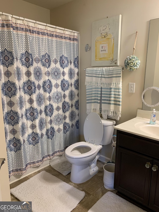 bathroom with tile patterned flooring, vanity, toilet, and walk in shower